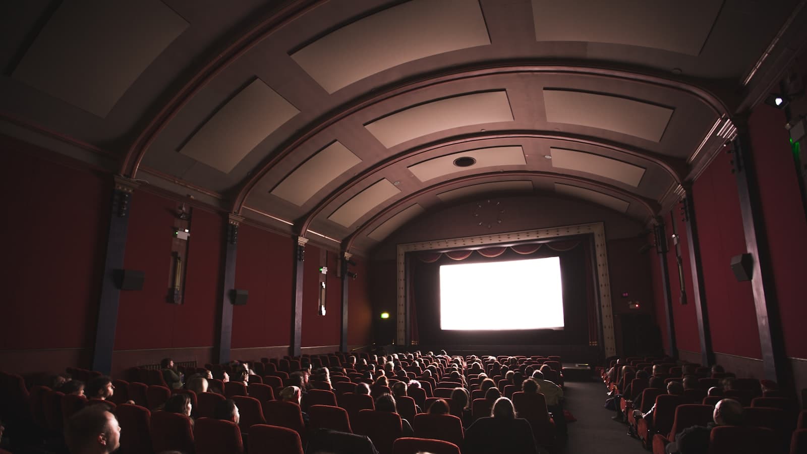 A full cinema auditorium of seated people facing a brightly lit screen