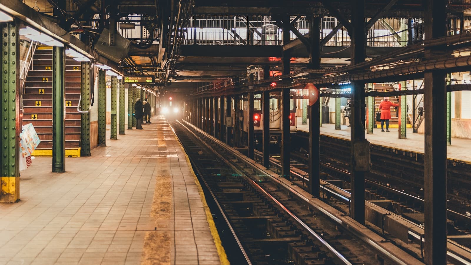 A metro platform and track with a train approaching in the distance